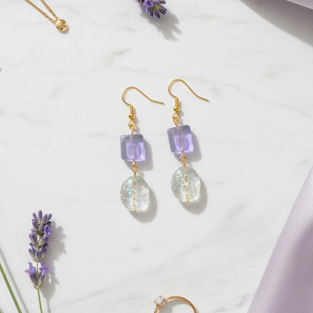 Pair of earrings with purple and clear beads on a gray background