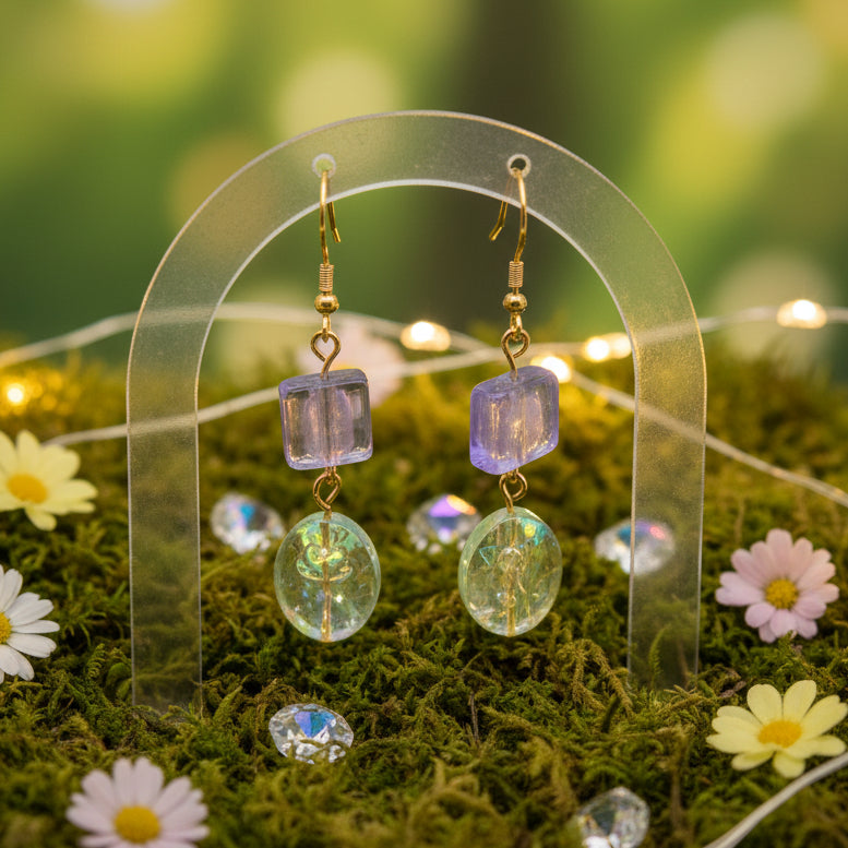Pair of earrings with purple and clear beads on a gray background