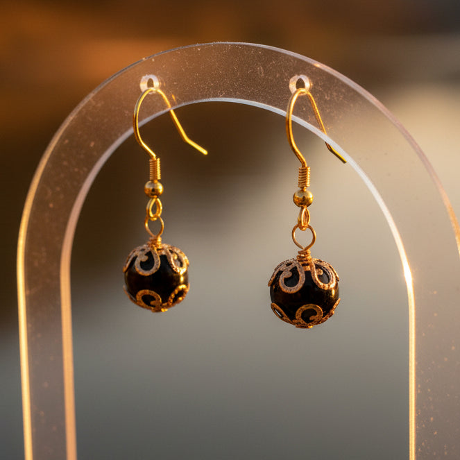 Pair of gold and black earrings on a gray background