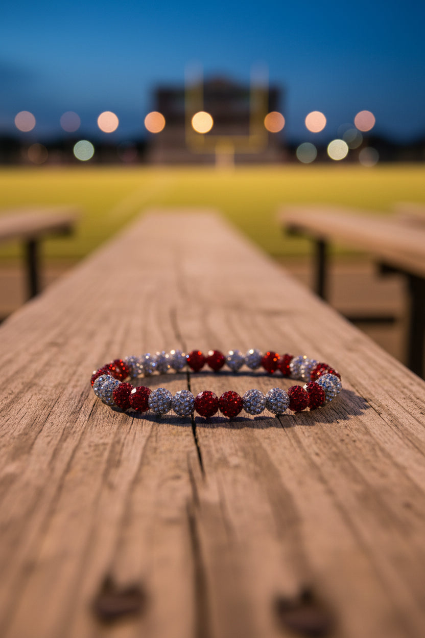 A beaded stretch bracelet featuring alternating red and silver faceted beads, displayed on a plain light gray surface.