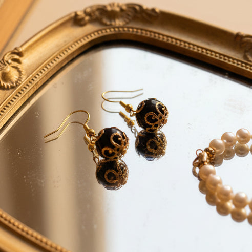 Pair of black earrings with gold accents on a gray background