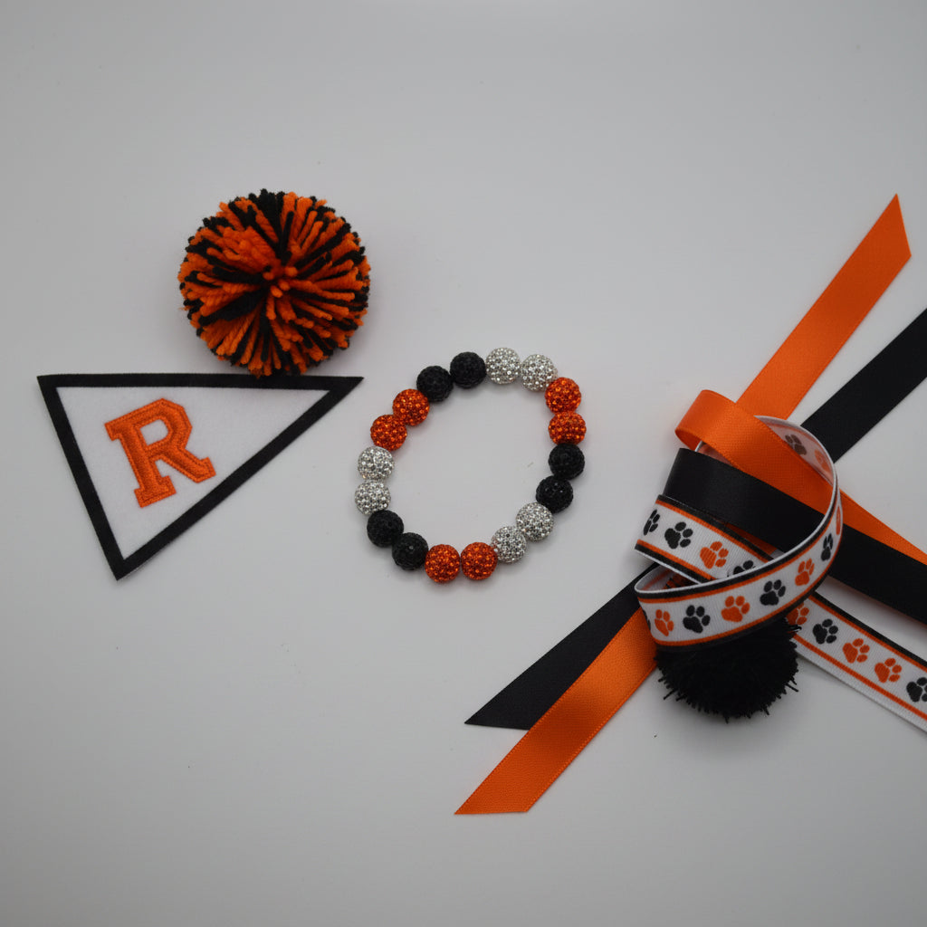 A beaded stretch bracelet featuring alternating black, orange, and silver rhinestone-covered round beads, displayed on a neutral light gray background.
