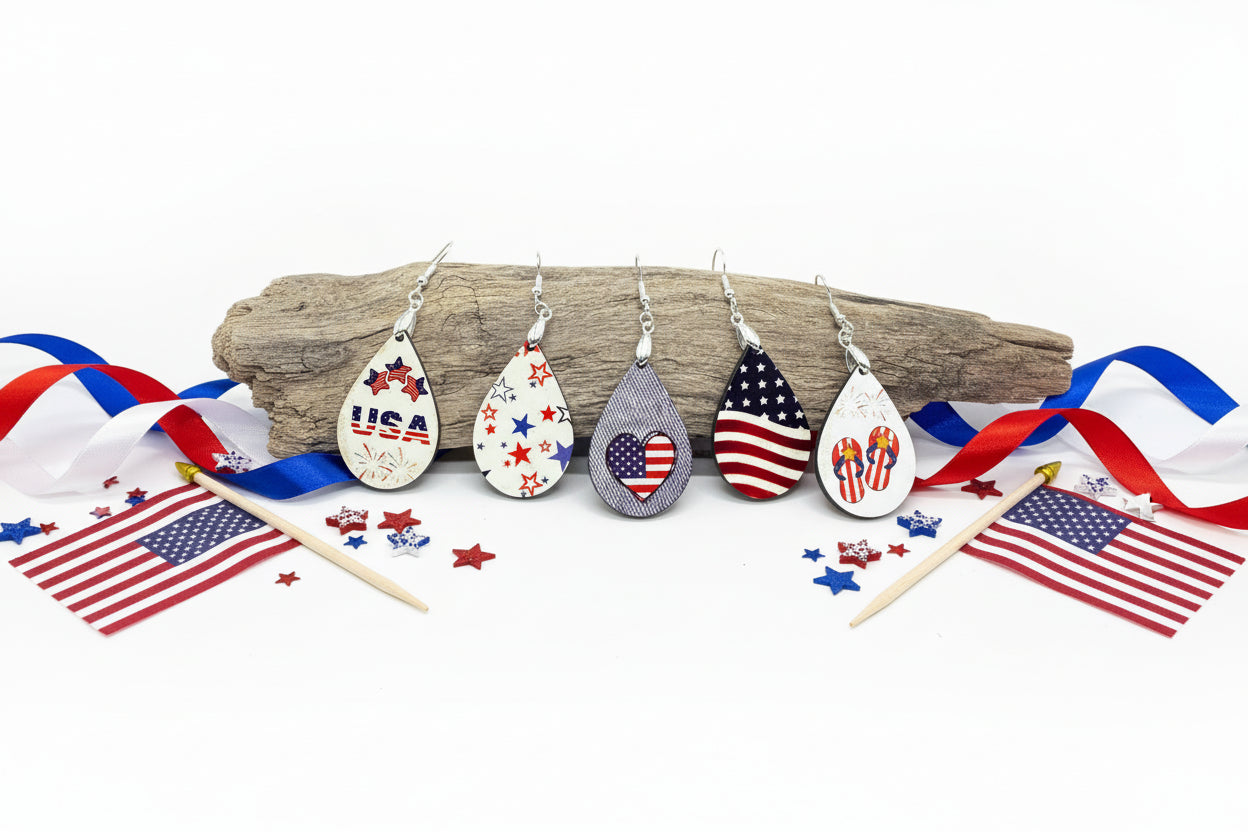A pair of sublimation earrings featuring a patriotic design with red, white, and blue colors, displayed on a wooden branch.