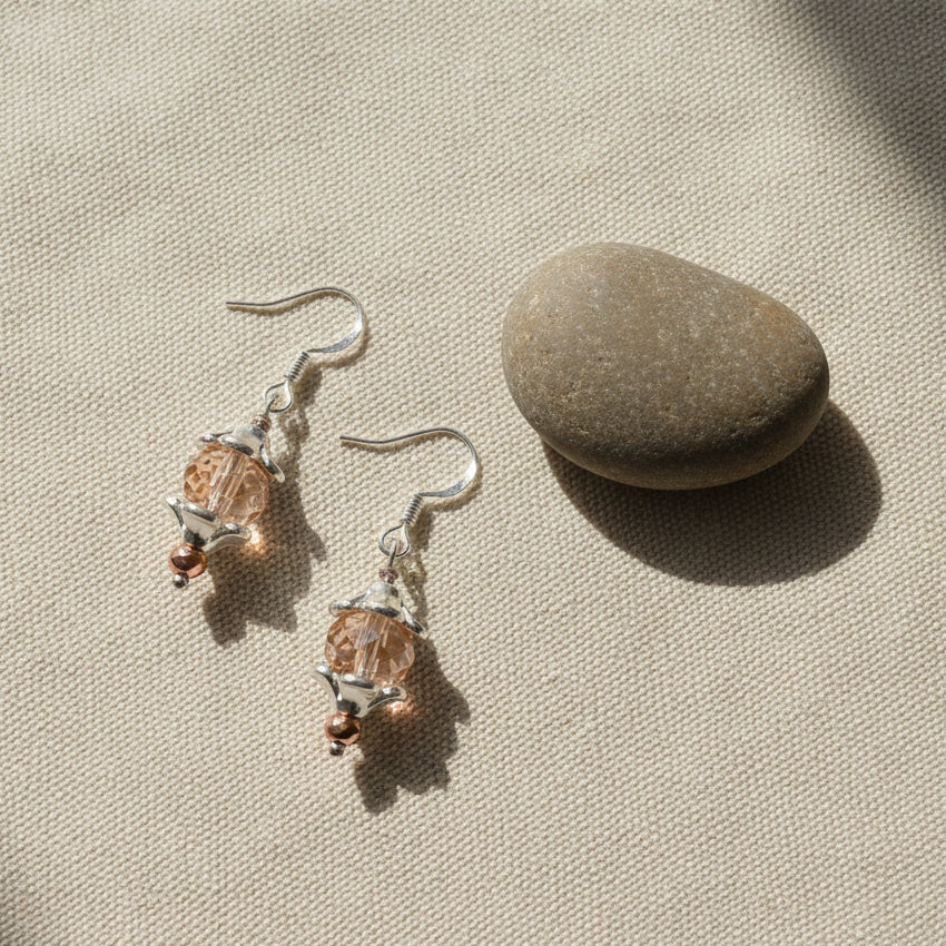 Pair of earrings with pink gemstones on a gray background