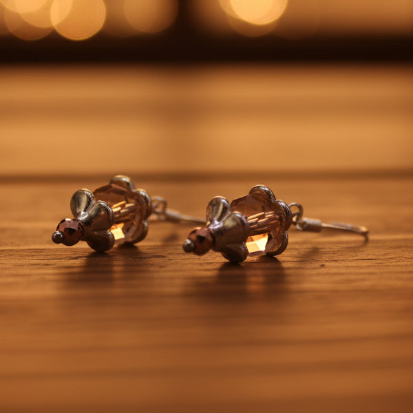 Pair of earrings with peach-colored beads on a gray background