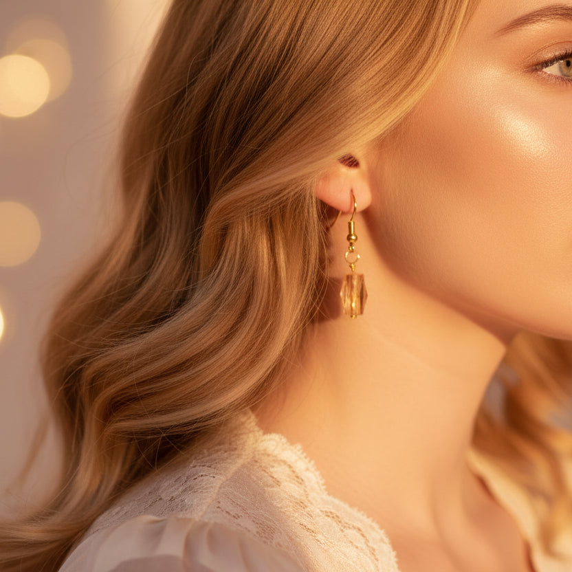 Pair of earrings with peach-colored beads on gold hooks against a gray background