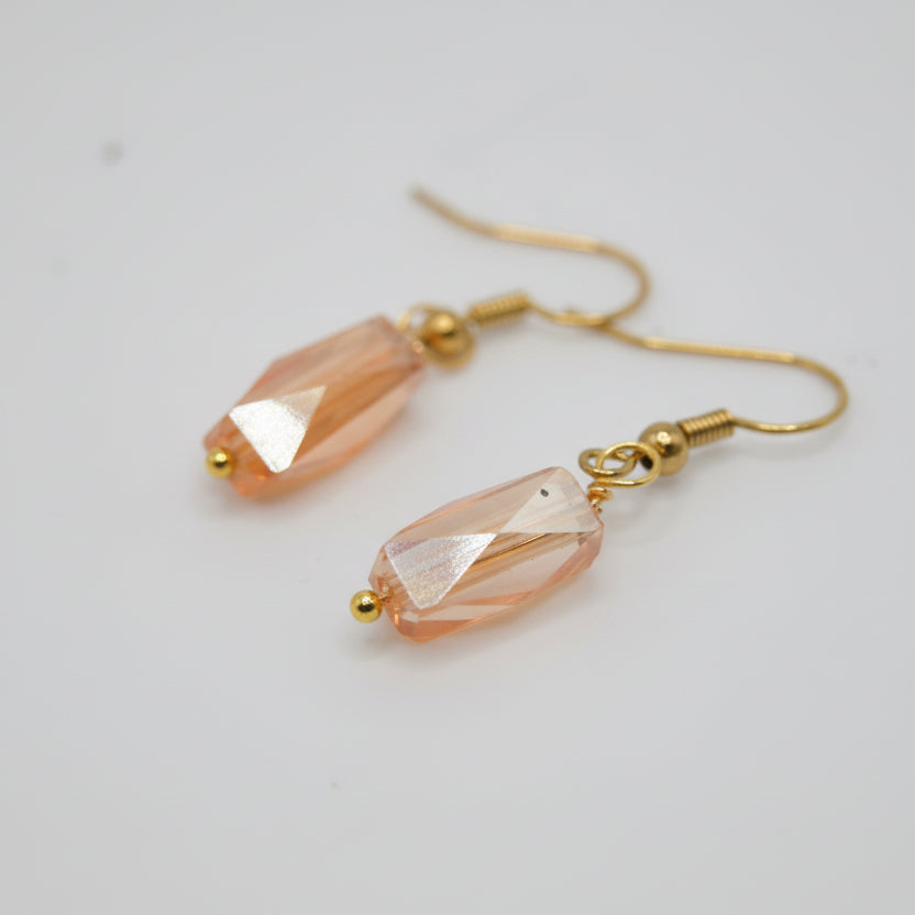 Pair of gold earrings with pink gemstones on a gray background