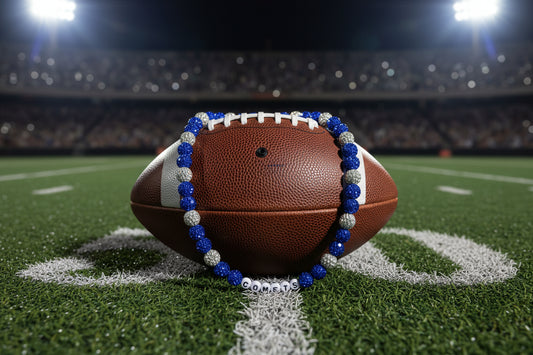 A beaded necklace with royal blue and silver rhinestone-covered beads, featuring a white bead with the word 'COMETS' spelled out in black letters, displayed on a white background.