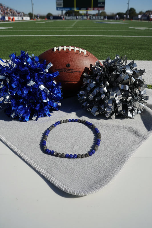 A beaded necklace made of alternating dark metallic and deep blue faceted beads, arranged in a circle on a plain light gray background.