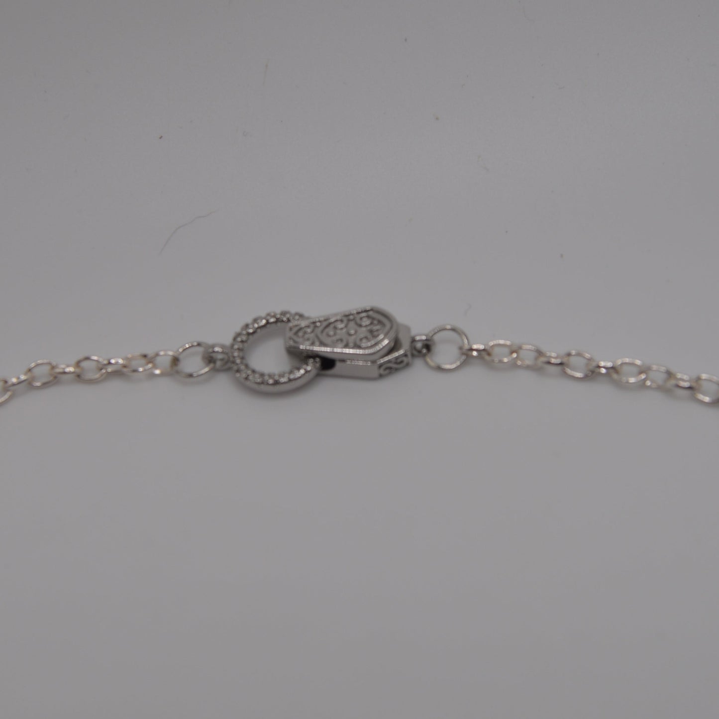 Silver necklace chain with clasp on a gray background