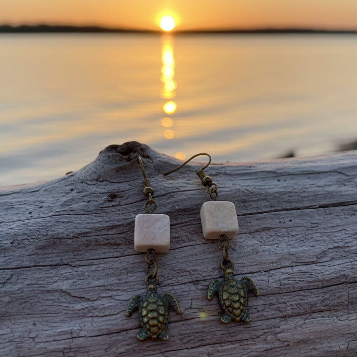 Turtle-themed earrings on a 'River Inspired' branded card against a gray background