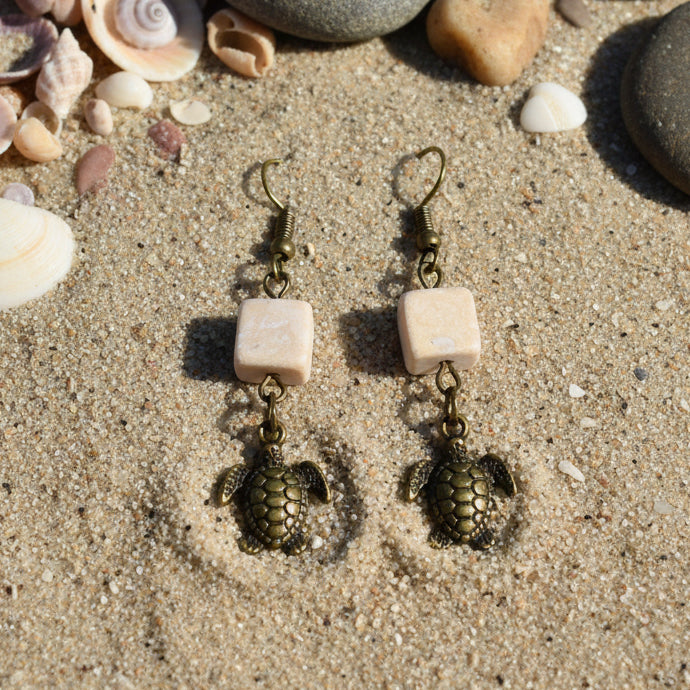 Turtle-shaped earrings on a 'River Inspired' branded card against a gray background