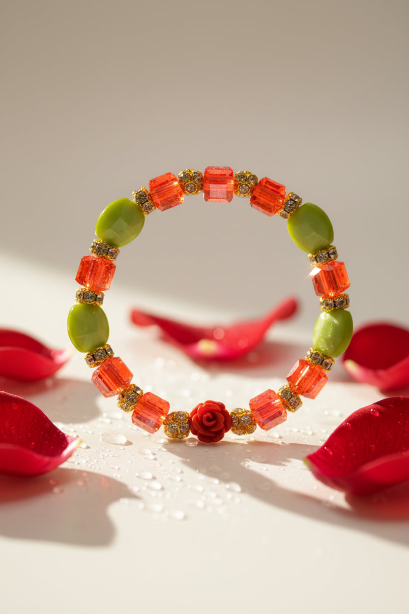 A beaded stretch bracelet featuring translucent red and orange beads, a red rose centerpiece, and lime green beads with gold glitter accents, set against a plain light gray background.