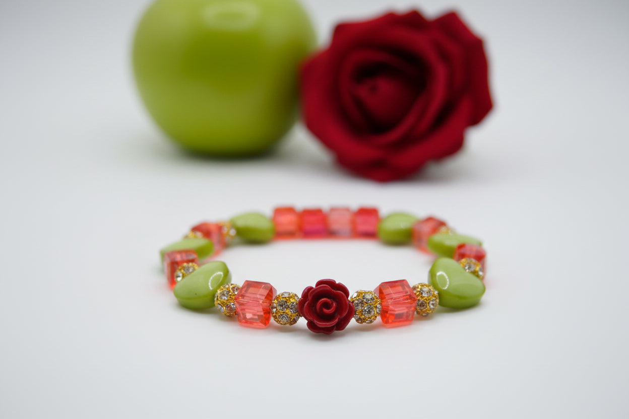 A beaded stretch bracelet featuring lime green and translucent red-orange beads, including a central red rose bead and small gold rhinestone accents, displayed on a neutral light gray background.