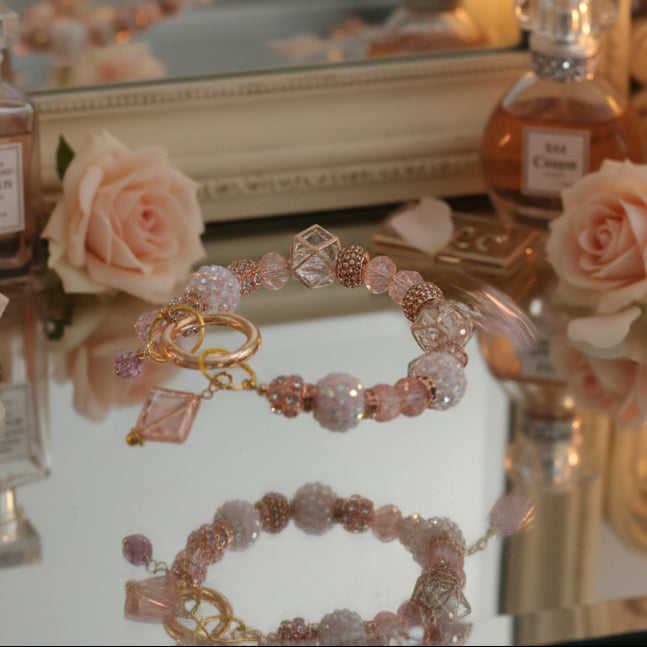 Beaded bracelet with pink and gold elements on a white background