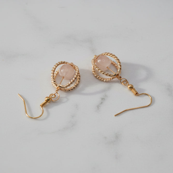 Gold earrings on a gray background