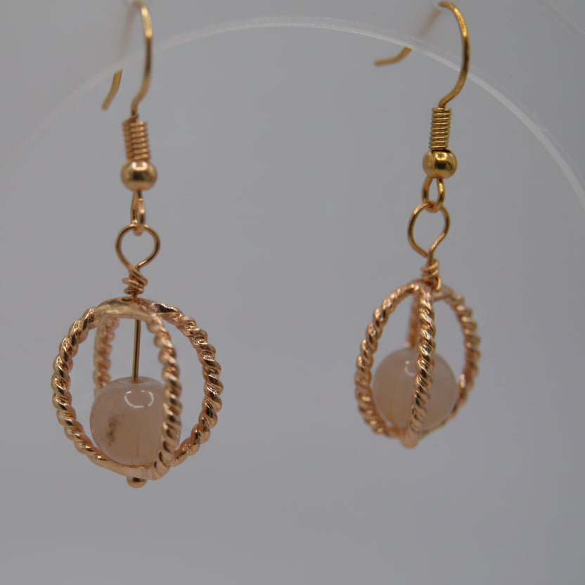 Gold hoop earrings with a central bead on a gray background
