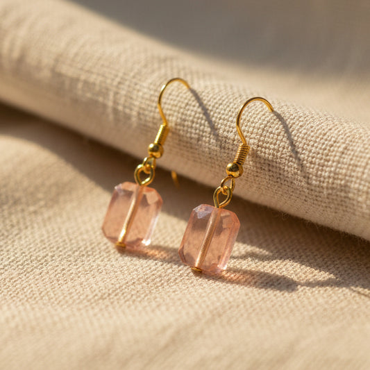 Pair of pink beaded earrings with gold hooks on a gray background