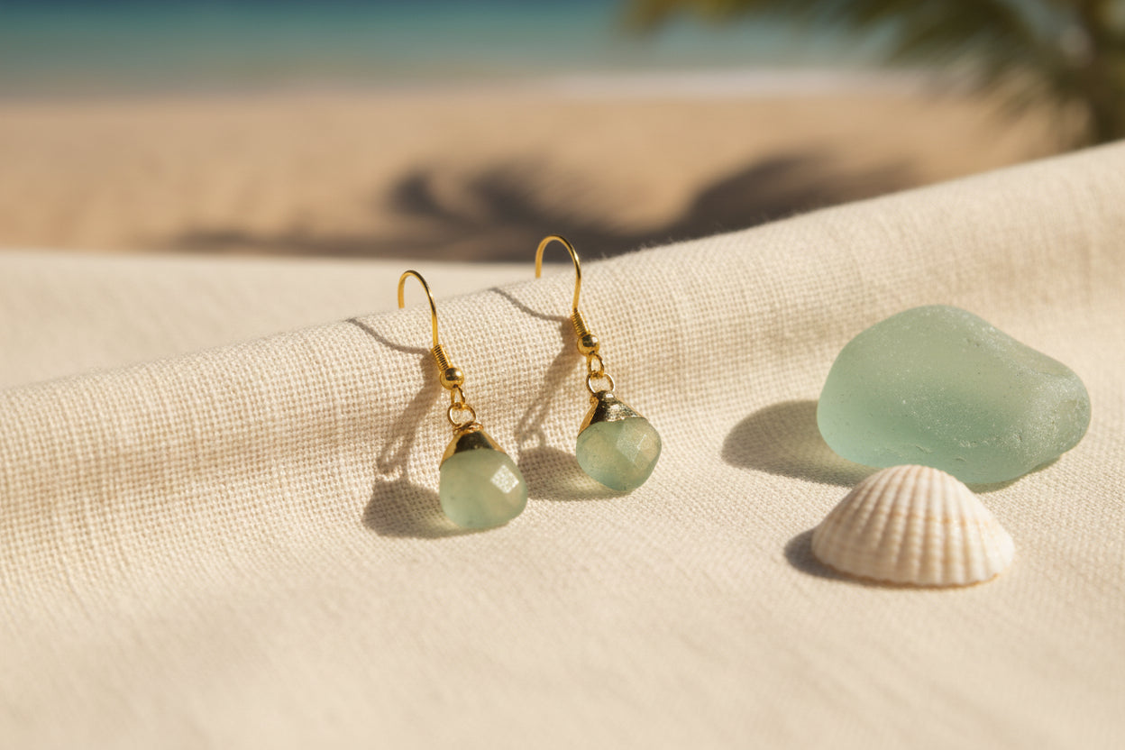 A pair of gold-tone dangle earrings with irregular light green stone pendants, displayed on a clear acrylic stand against a plain light gray background.