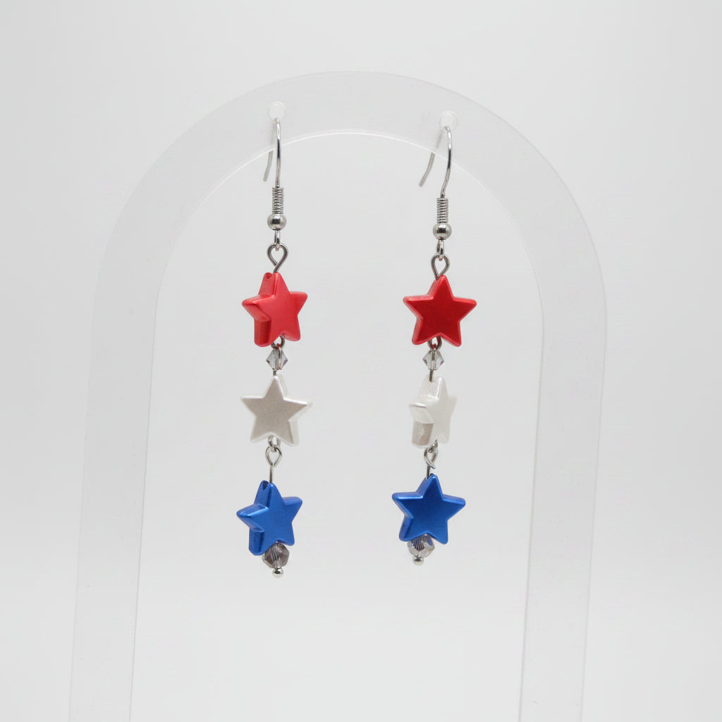 Star-shaped earrings with red, blue, and clear beads on a gray background