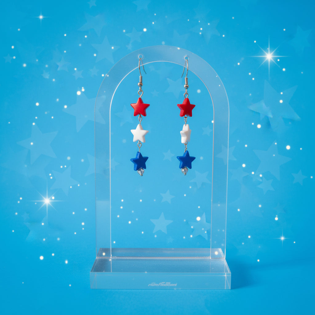 Star-shaped earrings with red, blue, and silver beads on a clear stand against a gray background