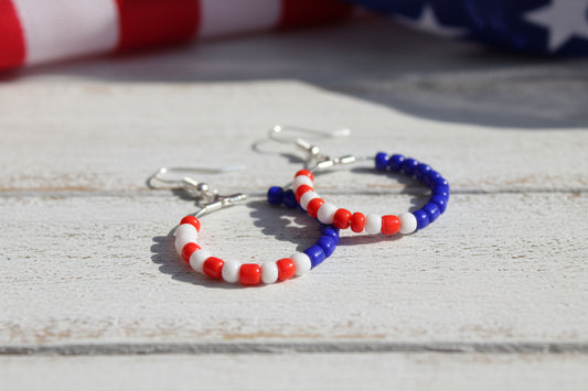 Pair of beaded hoop earrings with red, white, and blue beads on a gray background