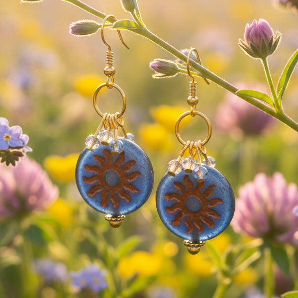 Pair of earrings with blue and gold components on a gray background