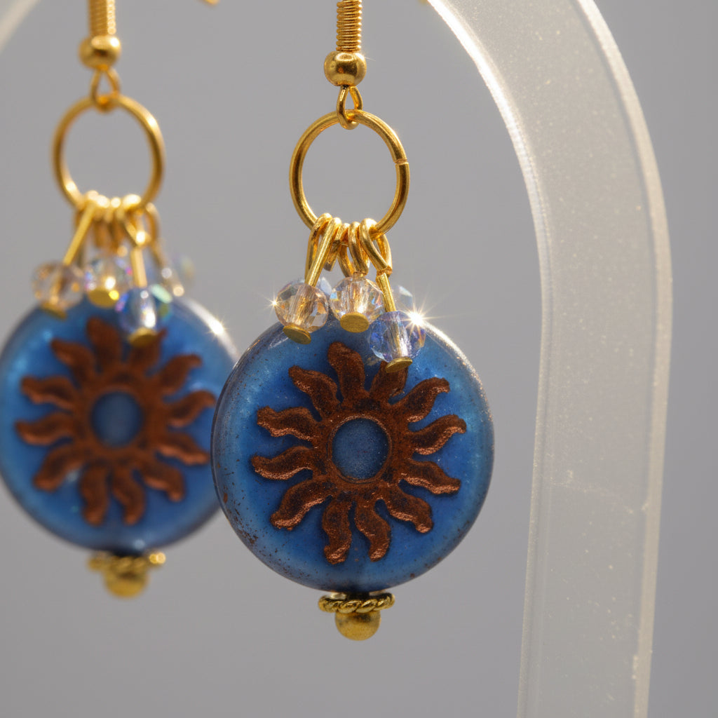 Blue floral earrings with gold accents on a clear background