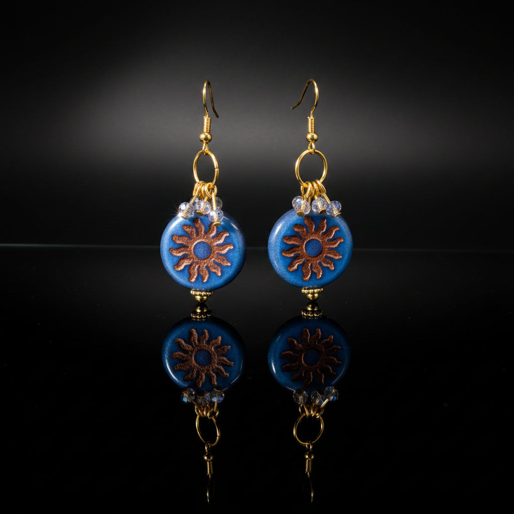 Pair of blue beaded earrings with gold accents on a gray background