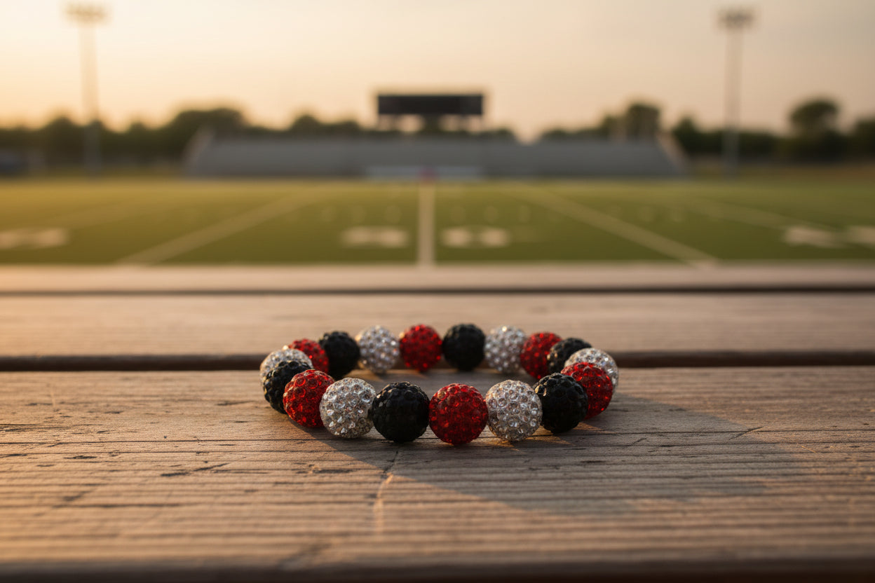 A beaded stretch bracelet featuring alternating red, black, and silver rhinestone-covered round beads, displayed on a neutral gray background.