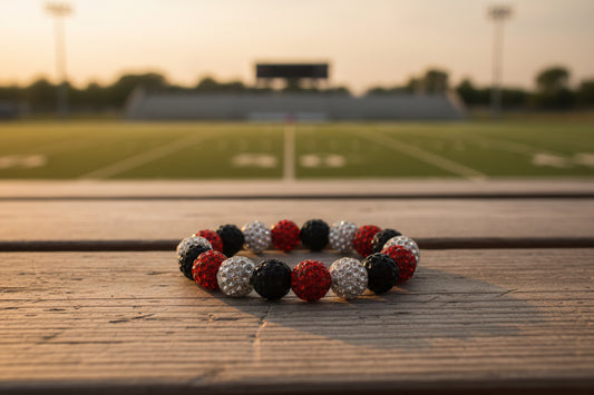 A beaded stretch bracelet featuring alternating red, black, and silver rhinestone-covered round beads, displayed on a neutral gray background.