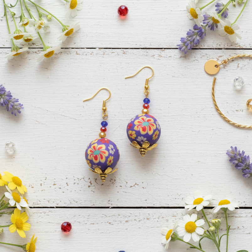 Colorful floral-patterned spherical earrings with gold accents on a gray background