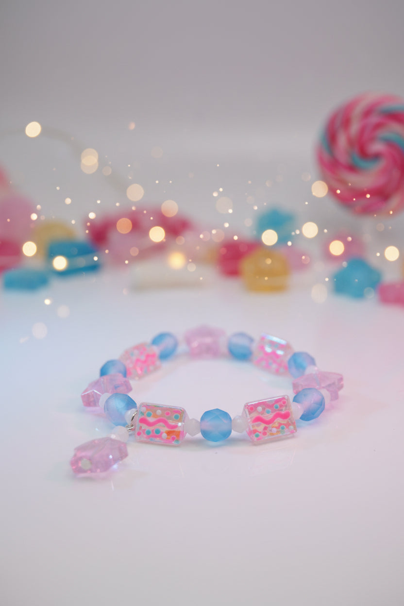 A beaded stretch bracelet featuring light blue faceted beads, pink faceted beads, and rectangular glass beads with colorful wavy patterns, shown on a plain light gray background.